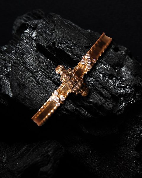 Thin gold bracelet with a small lakshmi figure and white stone clusters. Photographed at the shop.