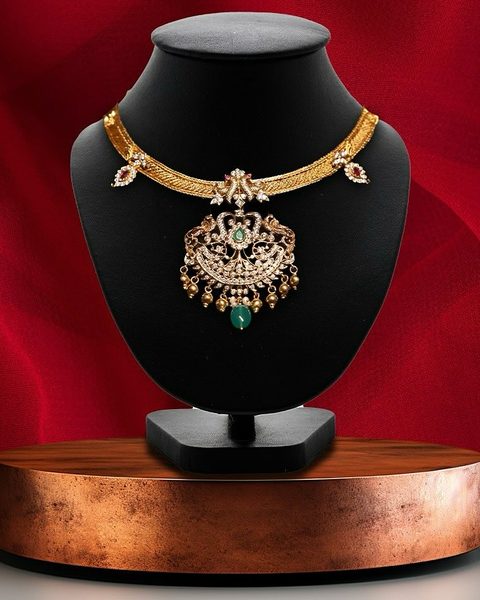 Flat gold chain necklace with cz peacock pendant, green centre stone and gold bead drops. Photographed at the shop.