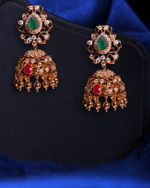 Pair of cz jhumkas with emerald pear tops, ruby accents and gold ball drops. Photographed at the shop.