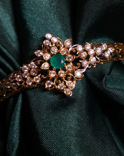 Rose gold bracelet with cz flower cluster and green centre stone on green silk. Photographed at the shop.