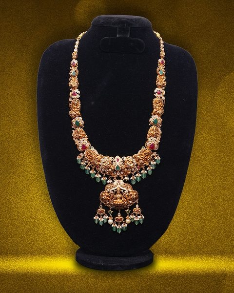 Nakshi haram with Lakshmi pendant, cz and ruby accents, emerald bead drops. Photographed at the shop.