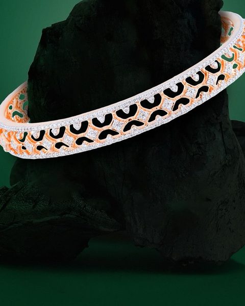 Rose gold bangle with white stone lattice pattern on charcoal rock. Photographed at the shop.