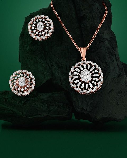 Rose gold round sunburst diamond pendant with chain and matching studs on charcoal. Photographed at the shop.