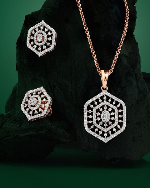 Rose gold hexagonal diamond pendant with chain and matching studs on charcoal. Photographed at the shop.