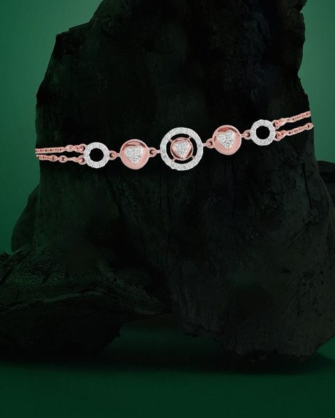 Rose gold diamond bracelet with circle and heart links on charcoal rock. Photographed at the shop.