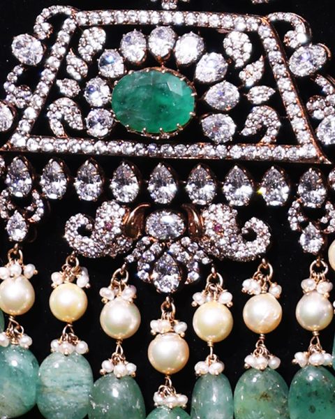 Macro of cz pendant with emerald oval centre, pear cz row, pearl and emerald fringe. Photographed at the shop.
