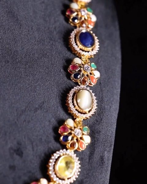 Navaratna necklace with oval coloured stones in white stone halos and flower links. Photographed at the shop.