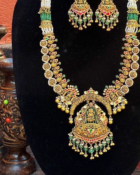 Nakshi haram with lakshmi pendant, pearl and emerald bead sections, matching lakshmi earrings. Photographed at the shop.