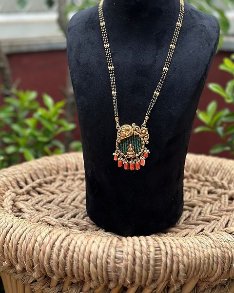 Three strand black bead chain with small Lakshmi pendant and coral drops. Photographed at the shop.