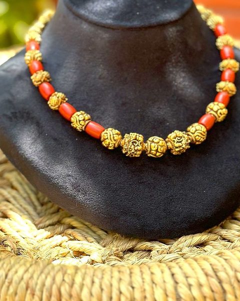 Short necklace of carved nakshi gold beads alternating with coral beads. Photographed at the shop.