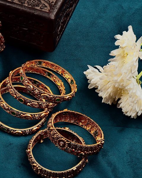 Set of antique gold bangles with emerald stones and coin floral motifs. Photographed at the shop.