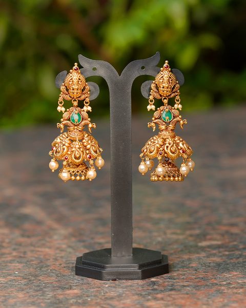 Antique gold jhumkas with lakshmi studs, peacock motifs, green stone and pearl drops. Photographed at the shop.