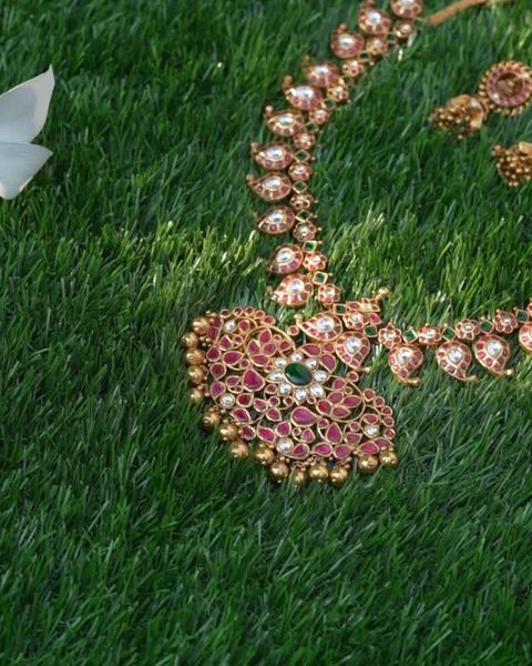 Kempu mango motif necklace with white stones, green centre and gold bead clusters. Photographed at the shop.
