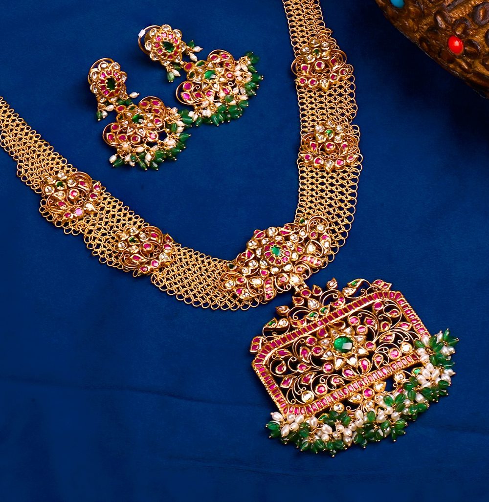 Kempu ruby and uncut stone haram with matching jhumkas on blue velvet.