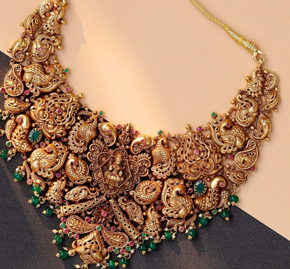 Antique gold nakshi choker with peacock and Lakshmi work and emerald beads.